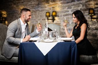 A man and woman sitting at a table with wine glasses.